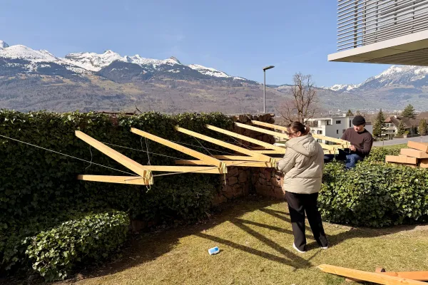 Drei junge Menschen bauen eine Konstruktion aus Holz 