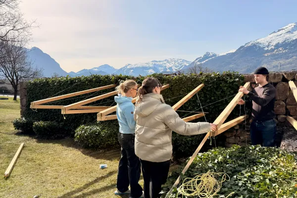 Drei junge Menschen bauen eine Konstruktion aus Holz 