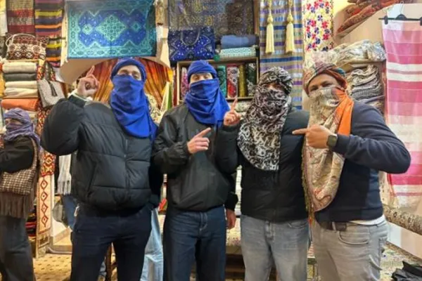 Vier Personen mit Tüchern im Laden vor bunten Stoffen.