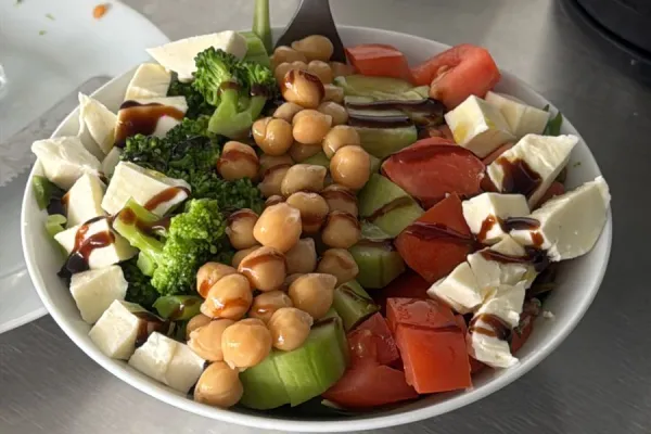 Bowl of salad with chickpeas, vegetables, and cheese.