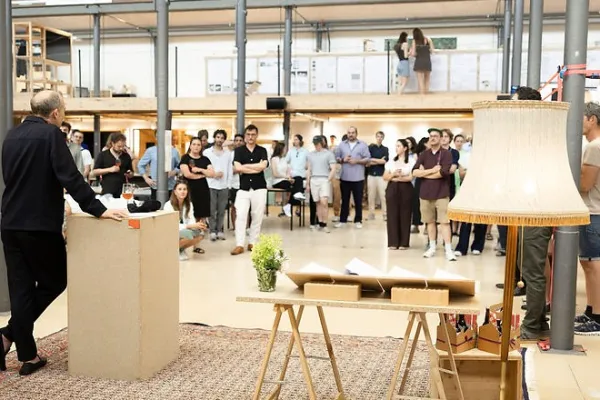 Publikum hört Mann mit Mikrofon in einem grossen Atelier zu 