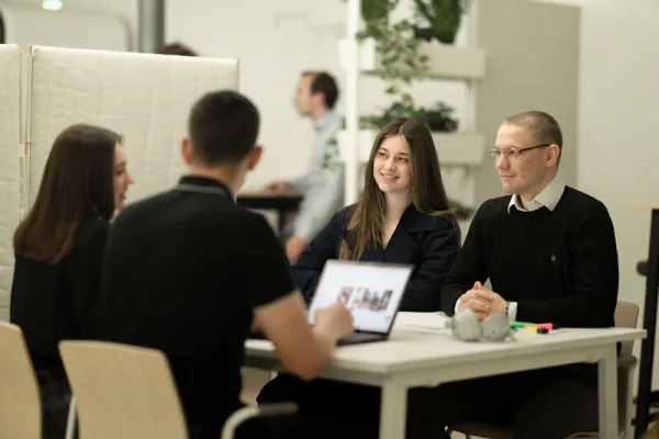 vier Personen sitzen am Tisch und besprechen etwas