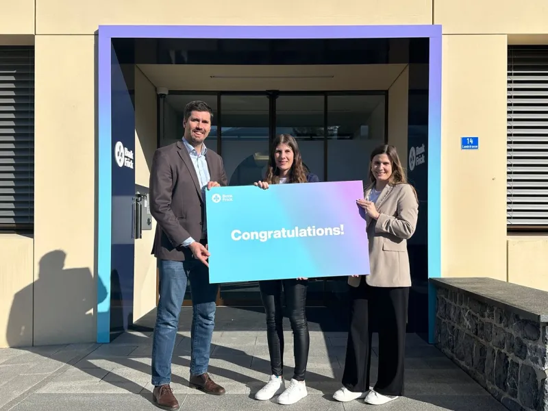Sabrina Zimmermann, die Stipendiatin von Bank Frick, steht vor dem Gebäude der Bank Frick, bereit, am CAS Blockchain und Fintech Programm teilzunehmen.