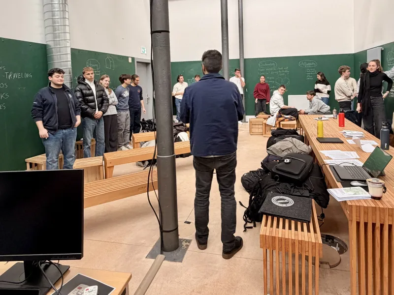 Mehrere Menschen stehen in einem grünen Raum mit Holzmöbeln
